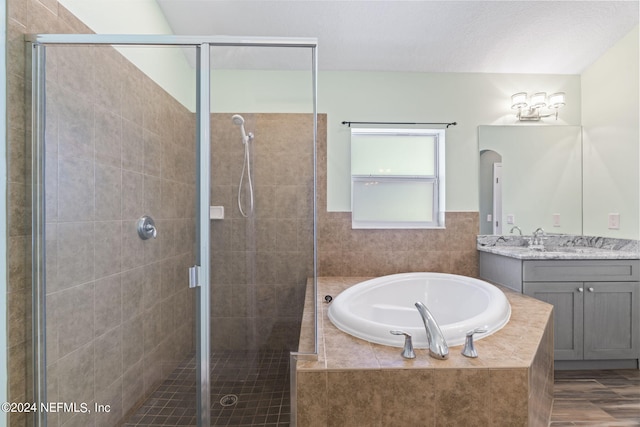 bathroom featuring a textured ceiling, a stall shower, vanity, and a bath