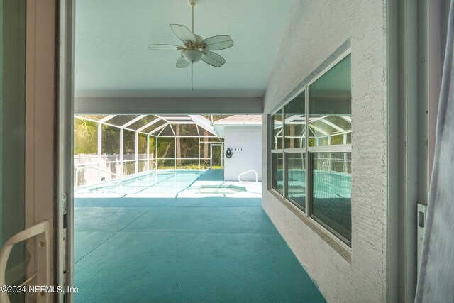 view of swimming pool featuring glass enclosure, a patio, and ceiling fan