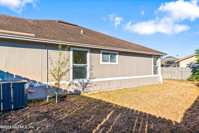 back of property with a yard and central air condition unit