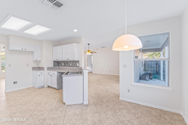 kitchen featuring hanging light fixtures, ceiling fan, decorative backsplash, white cabinetry, and kitchen peninsula