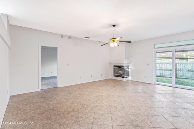 unfurnished living room featuring a multi sided fireplace, ceiling fan, and light tile patterned flooring