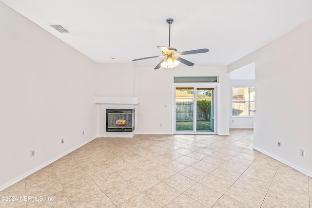 unfurnished living room with a multi sided fireplace, light tile patterned floors, and ceiling fan