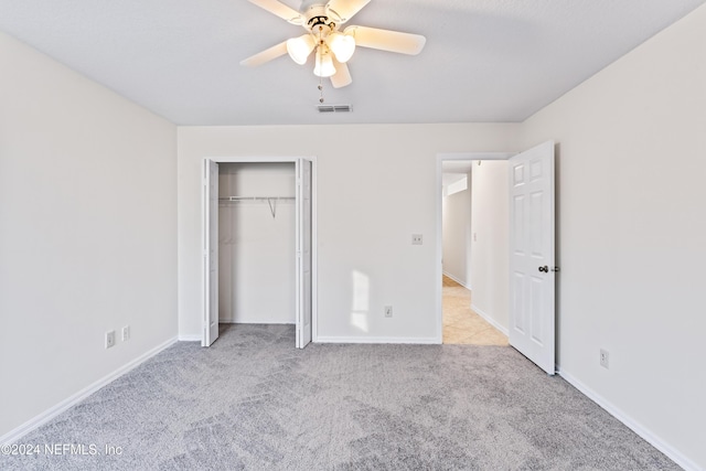 unfurnished bedroom featuring ceiling fan, a closet, and light colored carpet