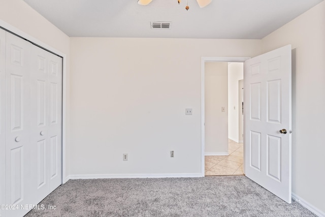 unfurnished bedroom with light carpet, a closet, and ceiling fan