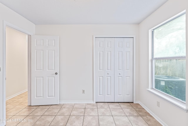 unfurnished bedroom with multiple windows, a closet, and light tile patterned floors