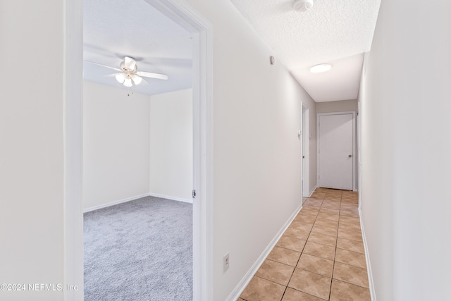 corridor featuring light tile patterned floors and a textured ceiling