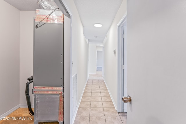 hallway with light tile patterned floors and a textured ceiling