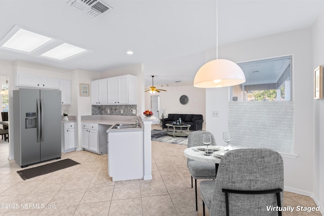 kitchen featuring backsplash, sink, decorative light fixtures, white cabinets, and stainless steel fridge with ice dispenser