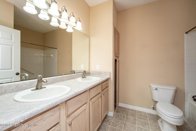 full bathroom with toilet, tiled shower / bath, vanity, and tile patterned floors