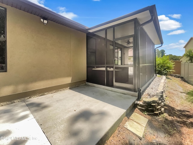 view of home's exterior with stucco siding, ceiling fan, fence, and a patio