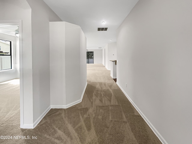 hall with carpet, visible vents, and baseboards