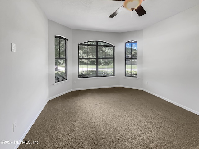 carpeted empty room featuring a ceiling fan and baseboards