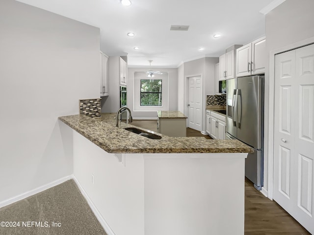 kitchen with appliances with stainless steel finishes, white cabinets, a sink, and a peninsula