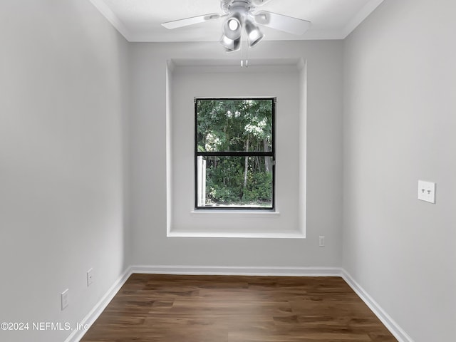 empty room featuring ornamental molding, dark wood finished floors, a ceiling fan, and baseboards