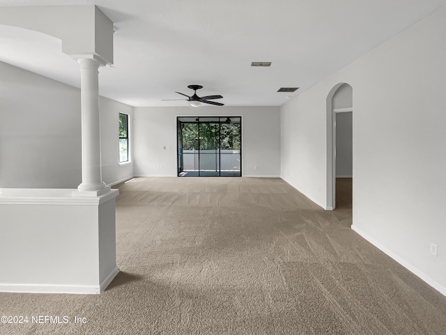 unfurnished room featuring decorative columns, visible vents, arched walkways, and light colored carpet