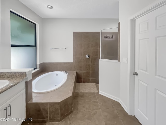 full bathroom with tile patterned flooring, a garden tub, vanity, and a walk in shower