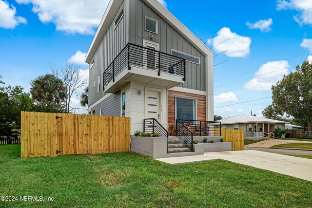 contemporary house with a balcony and a front yard