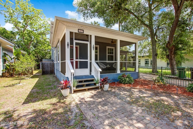 view of front of property with entry steps, a sunroom, and fence