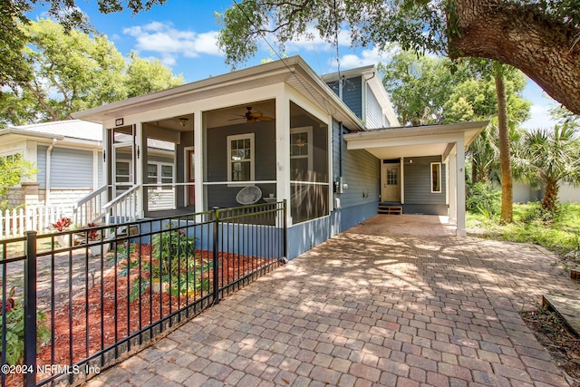 view of front of home featuring decorative driveway, a sunroom, ceiling fan, fence, and an attached carport