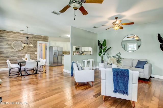 living room featuring light hardwood / wood-style floors, ceiling fan, and wooden walls