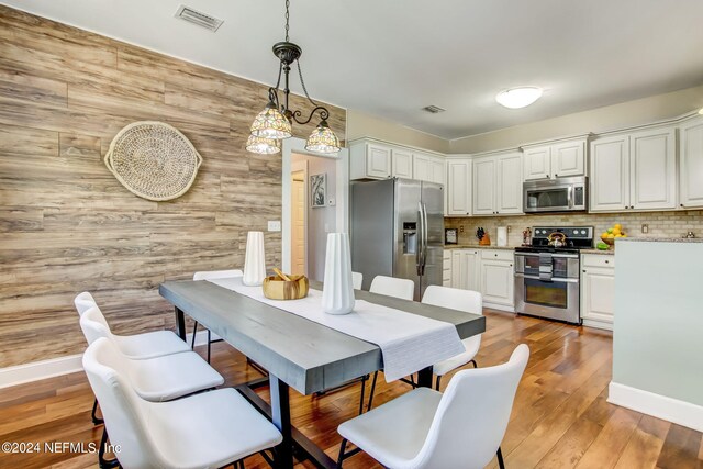 dining room featuring wood walls and light wood-type flooring