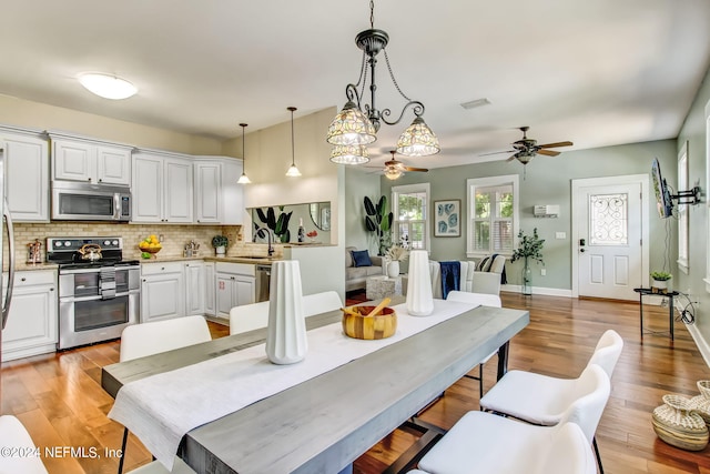 kitchen with appliances with stainless steel finishes, open floor plan, decorative light fixtures, light countertops, and white cabinetry