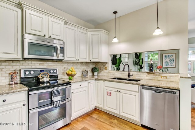 kitchen featuring sink, light wood-type flooring, appliances with stainless steel finishes, light stone countertops, and tasteful backsplash