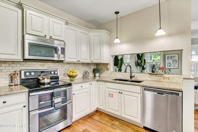 kitchen with pendant lighting, stainless steel appliances, white cabinetry, a sink, and a peninsula