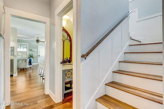 stairway with ceiling fan, baseboards, and wood finished floors