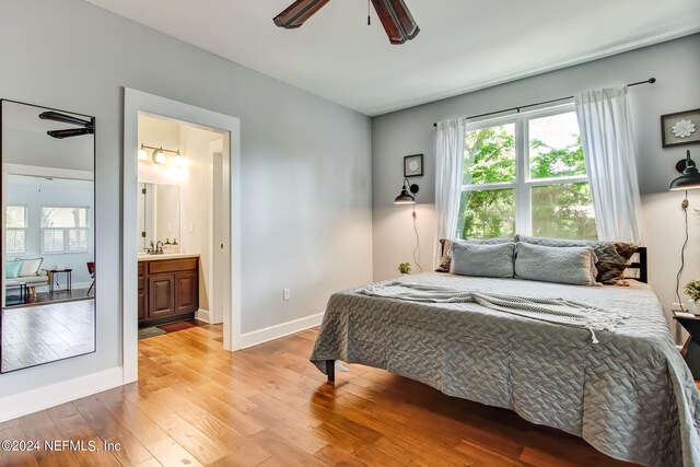 bedroom featuring ceiling fan, light wood-type flooring, ensuite bathroom, and sink