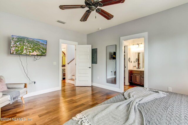 bedroom with hardwood / wood-style floors, connected bathroom, ceiling fan, and electric panel