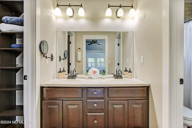 full bathroom with ceiling fan, a sink, toilet, and double vanity