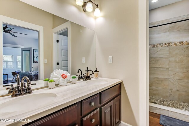 bathroom featuring ceiling fan, wood-type flooring, a tile shower, and vanity