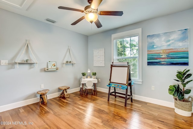 living area featuring visible vents, ceiling fan, baseboards, and wood finished floors