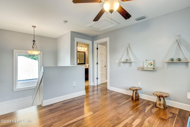 unfurnished room with baseboards, attic access, visible vents, and wood finished floors