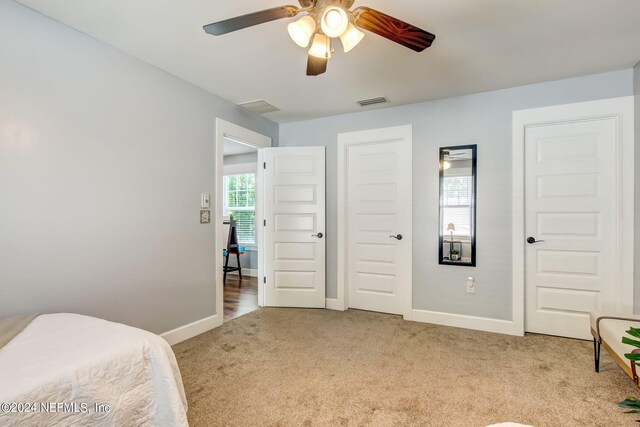 bedroom with ceiling fan, multiple windows, and light carpet