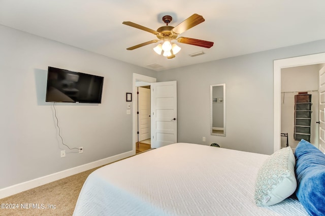 carpeted bedroom featuring ceiling fan, a spacious closet, and a closet