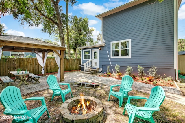 view of patio featuring entry steps, fence, a fire pit, and a gazebo