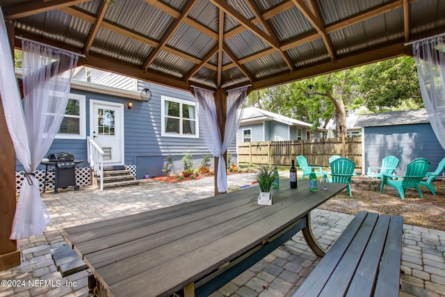 view of patio featuring a gazebo, entry steps, a grill, fence, and a fire pit