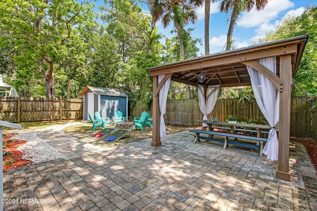 view of patio / terrace with a fenced backyard, an outdoor structure, a gazebo, and a storage unit