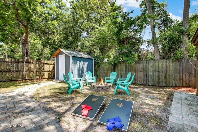 exterior space featuring a storage shed, an outdoor fire pit, a fenced backyard, and an outbuilding