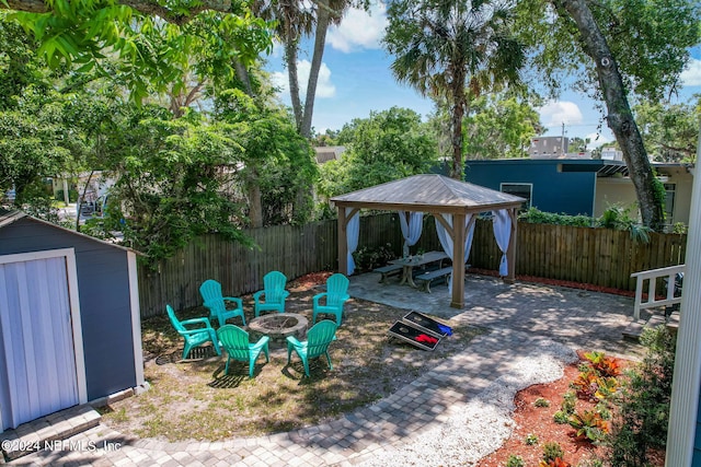 view of patio / terrace with an outbuilding, a fire pit, fence, a gazebo, and a shed