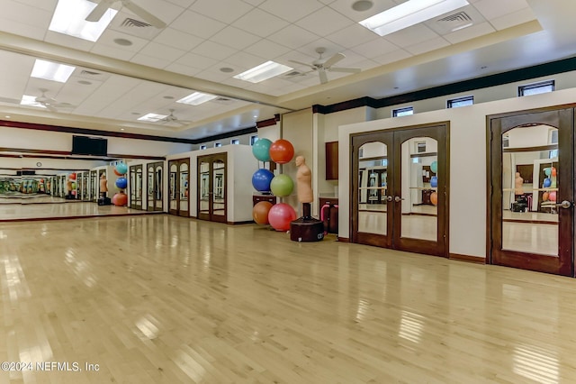 workout room featuring a paneled ceiling, ceiling fan, light hardwood / wood-style flooring, and french doors