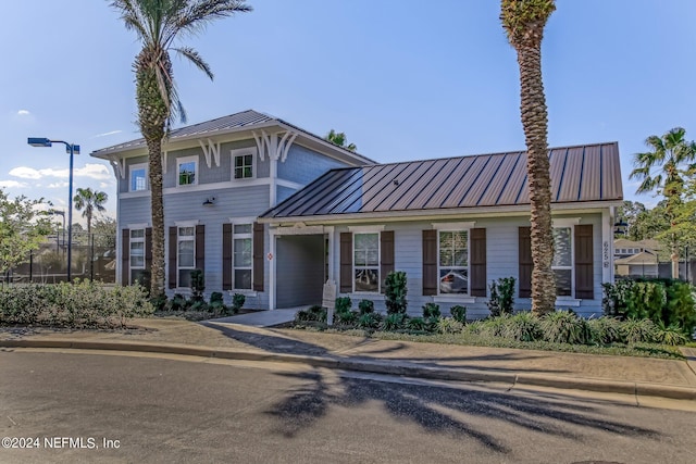 view of front of property featuring a standing seam roof, fence, and metal roof