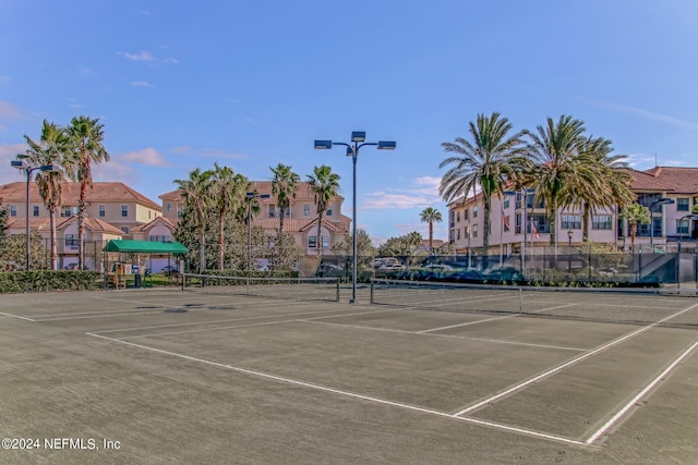 view of tennis court featuring a residential view and fence