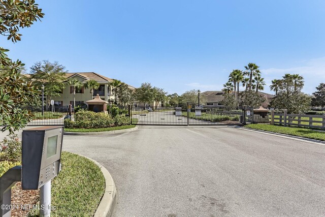 view of street with curbs, a gated entry, a residential view, and a gate