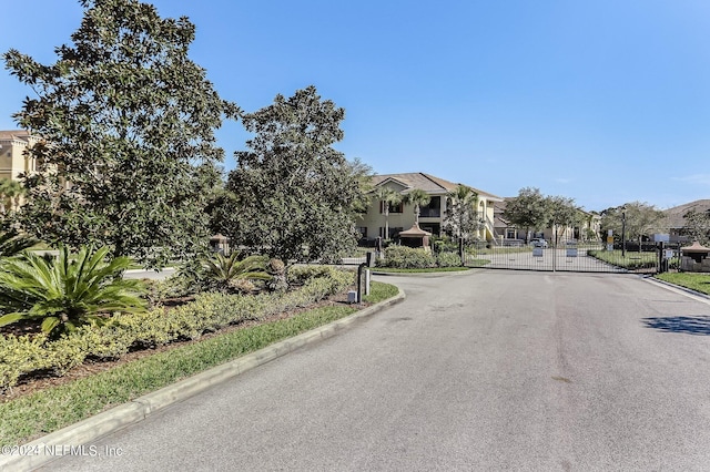 view of road with a residential view, a gate, curbs, and a gated entry