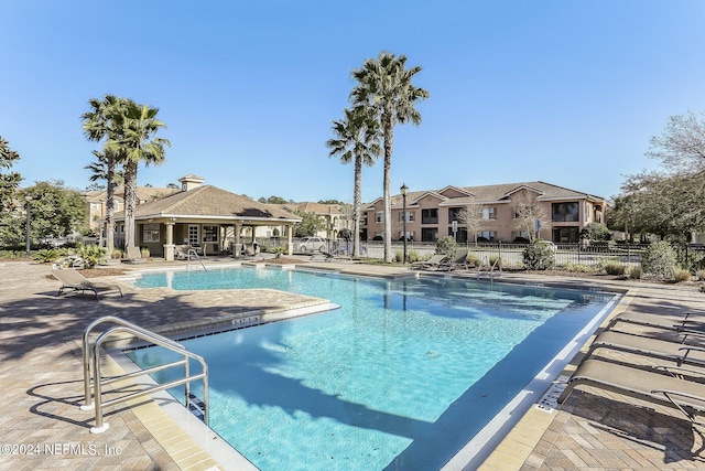 pool with a residential view, fence, and a patio