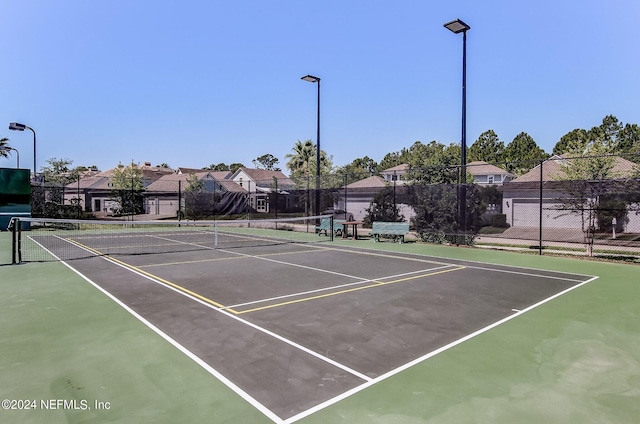 view of tennis court featuring a residential view and fence