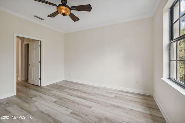 empty room with light wood-style floors, baseboards, visible vents, and crown molding